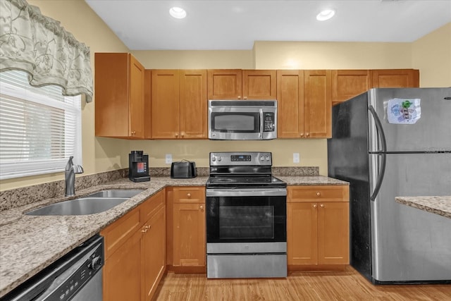 kitchen featuring a sink, light stone counters, light wood-style floors, stainless steel appliances, and recessed lighting