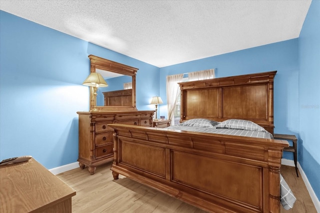 bedroom with a textured ceiling, baseboards, and light wood-style flooring