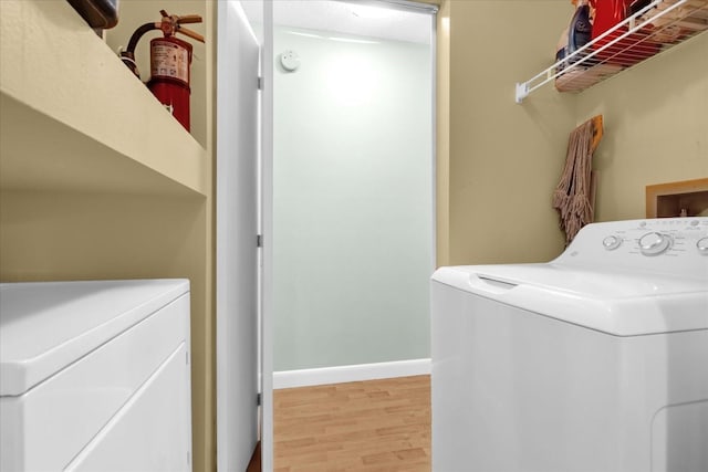 laundry room featuring baseboards, separate washer and dryer, laundry area, and wood finished floors