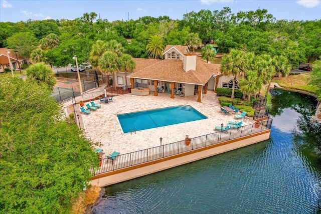 view of swimming pool featuring a water view, fence, a patio area, and a fenced in pool