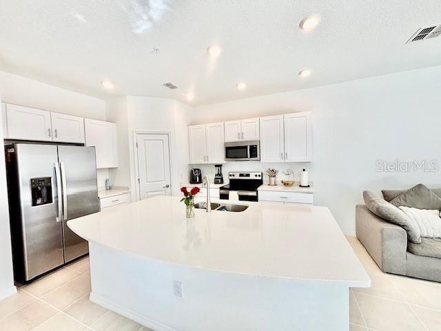 kitchen featuring appliances with stainless steel finishes, a center island with sink, a sink, light countertops, and white cabinets