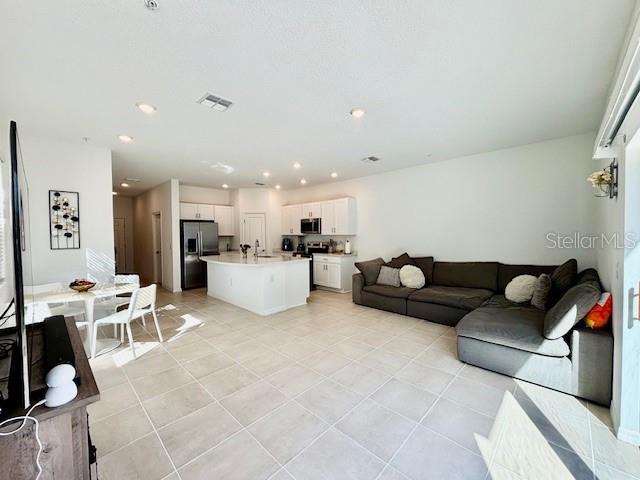 living room with recessed lighting, visible vents, and light tile patterned floors