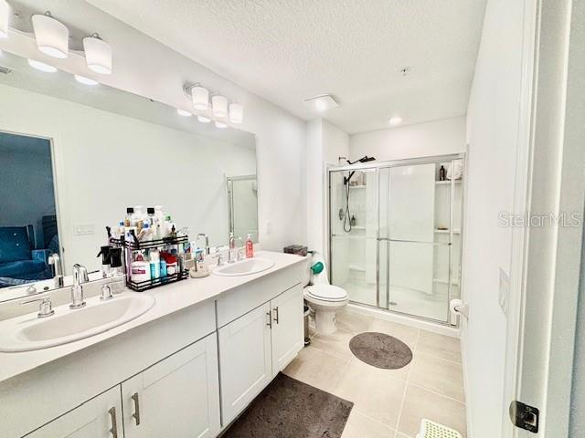 ensuite bathroom featuring a sink, tile patterned floors, and a shower stall