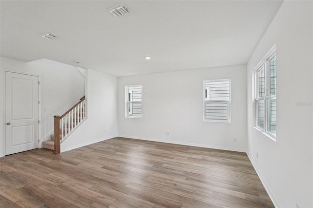 2467 Zuni Rd, Saint Cloud, FL 34771 - unfurnished room with stairway, healthy amount of natural light, wood finished floors, baseboards, and recessed lighting