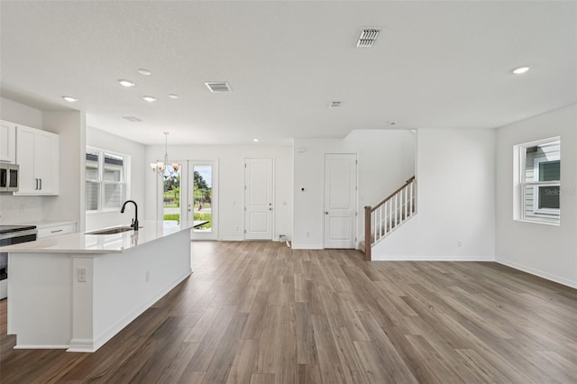 2467 Zuni Rd, Saint Cloud, FL 34771 - kitchen featuring a sink, range, stainless steel microwave, wood finished floors, and light countertops