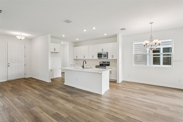 2467 Zuni Rd, Saint Cloud, FL 34771 - kitchen with stainless steel appliances, recessed lighting, light wood finished floors, white cabinets, and baseboards