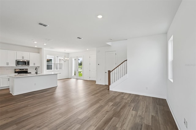 2467 Zuni Rd, Saint Cloud, FL 34771 - unfurnished living room with baseboards, wood finished floors, a chandelier, stairway, and recessed lighting