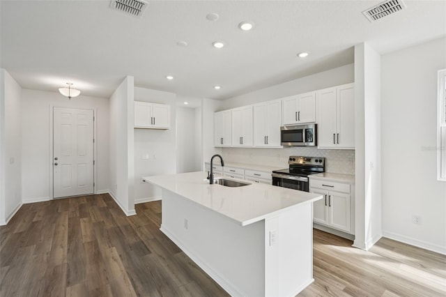 2467 Zuni Rd, Saint Cloud, FL 34771 - kitchen featuring stainless steel appliances, a sink, white cabinets, wood finished floors, and baseboards
