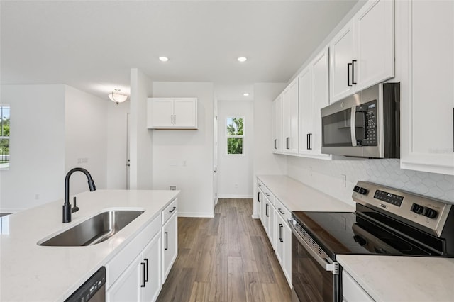 2467 Zuni Rd, Saint Cloud, FL 34771 - kitchen with stainless steel appliances, a sink, wood finished floors, recessed lighting, and white cabinetry