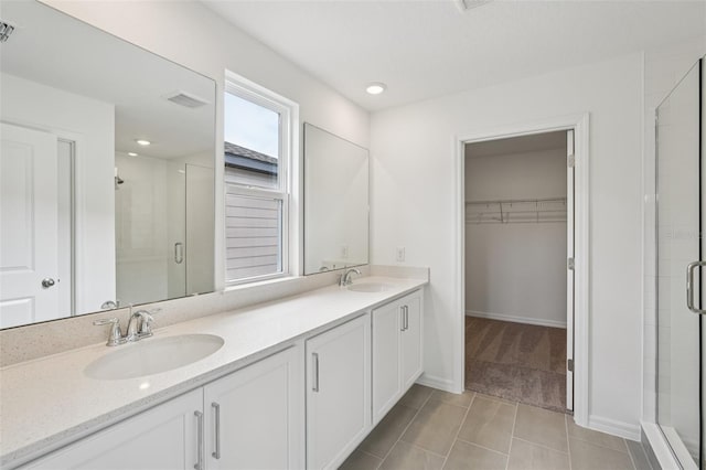 2467 Zuni Rd, Saint Cloud, FL 34771 - bathroom featuring a stall shower, double vanity, a spacious closet, tile patterned flooring, and baseboards