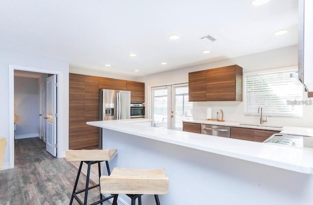 631 Trailwood Dr, Altamonte Springs, FL 32714 - kitchen featuring a breakfast bar, modern cabinets, brown cabinets, a sink, and appliances with stainless steel finishes