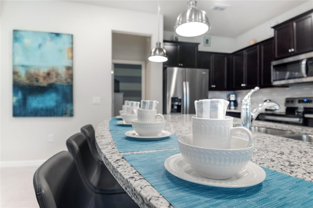 1820 Summer Dr, Davenport, FL 33897 - kitchen featuring a breakfast bar area, decorative light fixtures, appliances with stainless steel finishes, tasteful backsplash, and a sink