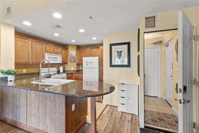 7630 Heritage Crossing Way Unit 302, Reunion, FL 34747 - kitchen with white appliances, a peninsula, a sink, recessed lighting, and dark stone counters