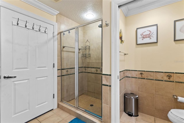 7630 Heritage Crossing Way Unit 302, Reunion, FL 34747 - bathroom featuring toilet, a shower stall, tile patterned flooring, tile walls, and wainscoting