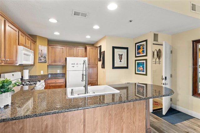 7630 Heritage Crossing Way Unit 302, Reunion, FL 34747 - kitchen featuring white appliances, a sink, baseboards, a peninsula, and wood finished floors