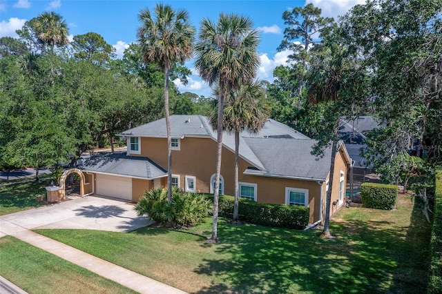 view of front of house featuring an attached garage, stucco siding, concrete driveway, a front lawn, and roof with shingles