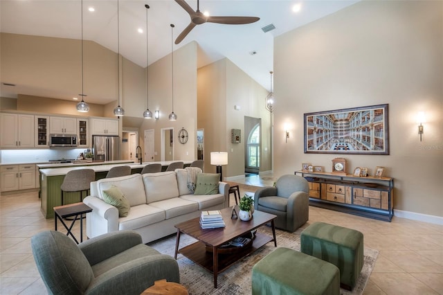 living room featuring high vaulted ceiling, visible vents, ceiling fan, light tile patterned floors, and baseboards