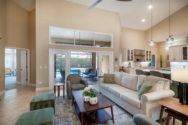 living area featuring baseboards, light tile patterned floors, and high vaulted ceiling