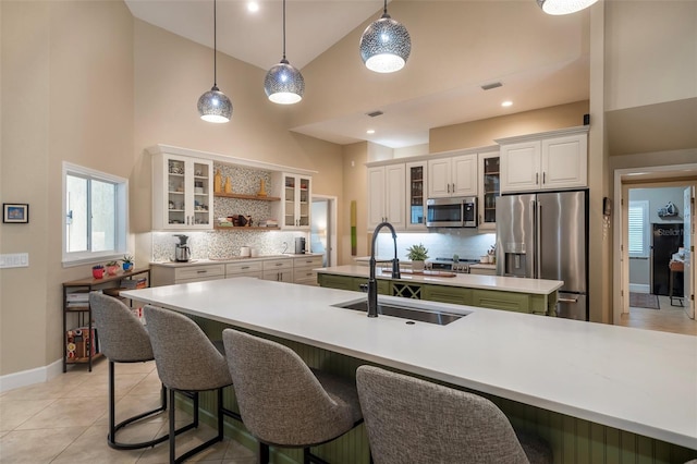 kitchen with backsplash, appliances with stainless steel finishes, a sink, and high vaulted ceiling