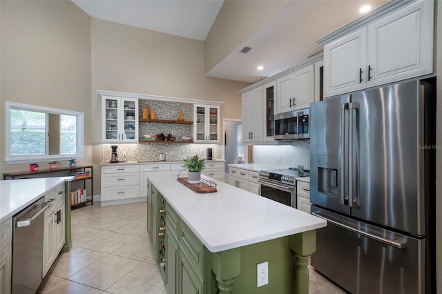 kitchen with stainless steel appliances, open shelves, backsplash, light countertops, and green cabinets