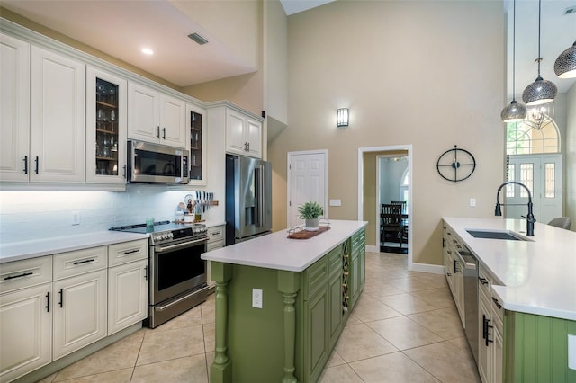 kitchen featuring a sink, tasteful backsplash, green cabinetry, white cabinetry, and appliances with stainless steel finishes