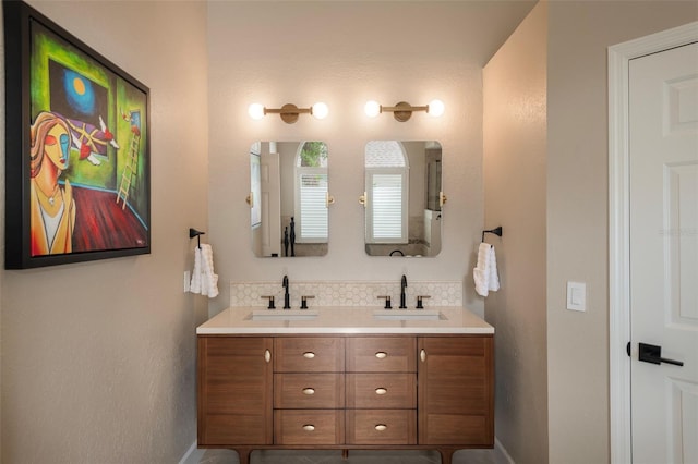 full bathroom featuring backsplash, baseboards, double vanity, and a sink