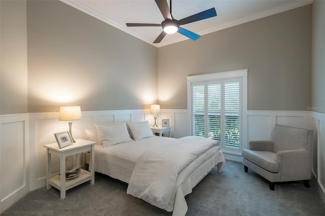carpeted bedroom featuring a decorative wall, crown molding, and wainscoting