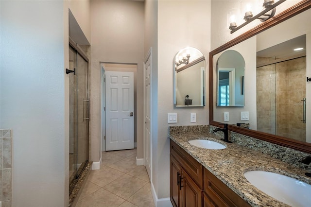 bathroom featuring a stall shower, tile patterned flooring, double vanity, and a sink