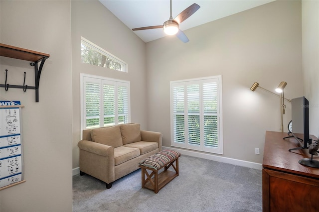 sitting room with a towering ceiling, carpet, baseboards, and a ceiling fan