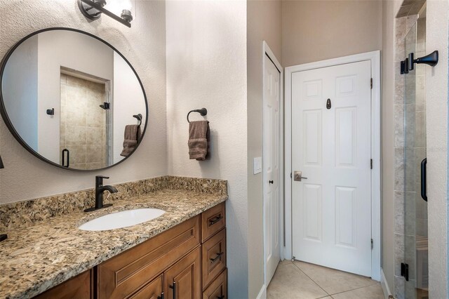 full bathroom featuring a stall shower, tile patterned flooring, a textured wall, and vanity