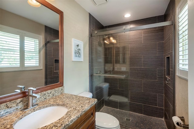 bathroom featuring toilet, vanity, and a stall shower