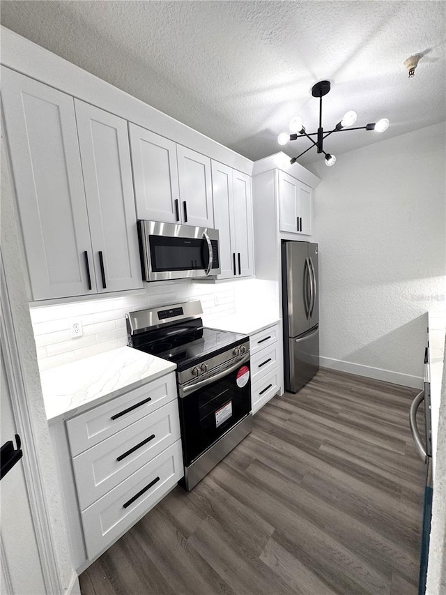 7147 Yacht Basin Ave Unit 119, Orlando, FL 32835 - kitchen featuring dark wood finished floors, white cabinetry, a chandelier, backsplash, and stainless steel appliances