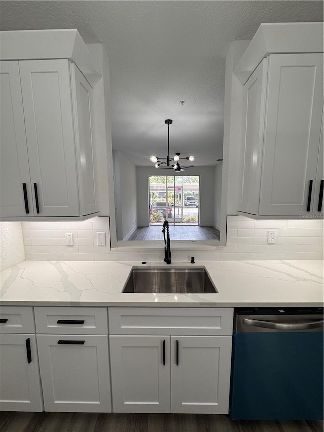 7147 Yacht Basin Ave Unit 119, Orlando, FL 32835 - kitchen with dishwashing machine, a sink, a notable chandelier, white cabinets, and decorative backsplash
