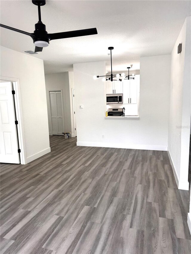 7147 Yacht Basin Ave Unit 119, Orlando, FL 32835 - unfurnished living room featuring dark wood-style flooring, ceiling fan with notable chandelier, and baseboards