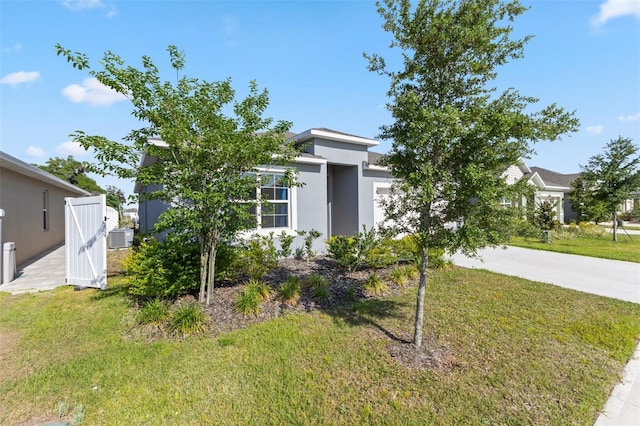 view of front of house with a front lawn, central AC, stucco siding, concrete driveway, and an attached garage