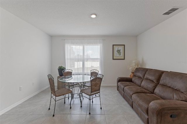 dining room featuring visible vents, a textured ceiling, baseboards, and light tile patterned floors