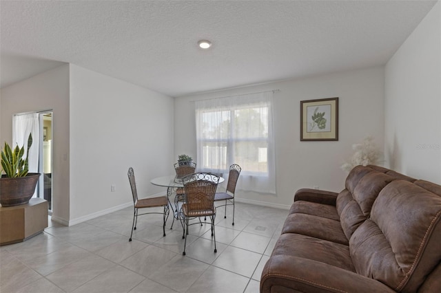 dining room featuring baseboards, a textured ceiling, and light tile patterned flooring