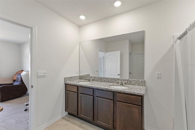 full bath with a sink, baseboards, and double vanity