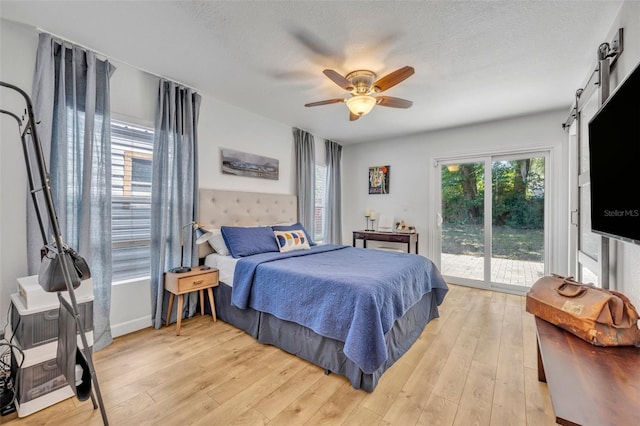 440 E Crystal Lake St, Orlando, FL 32806 - bedroom featuring a barn door, light wood finished floors, a textured ceiling, access to exterior, and a ceiling fan