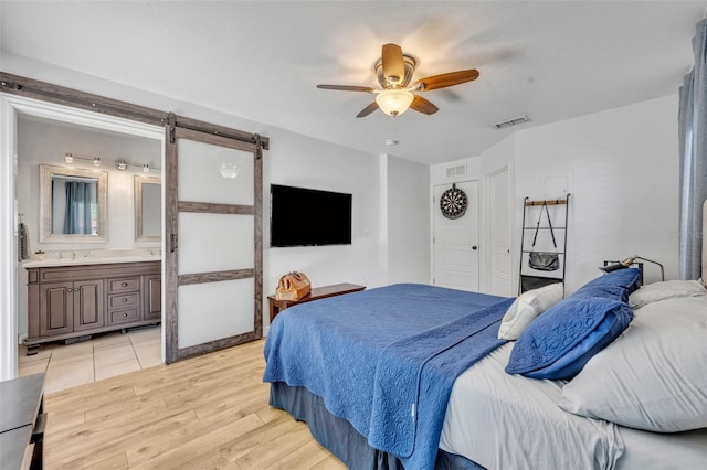 440 E Crystal Lake St, Orlando, FL 32806 - bedroom featuring visible vents, a barn door, light wood finished floors, and connected bathroom