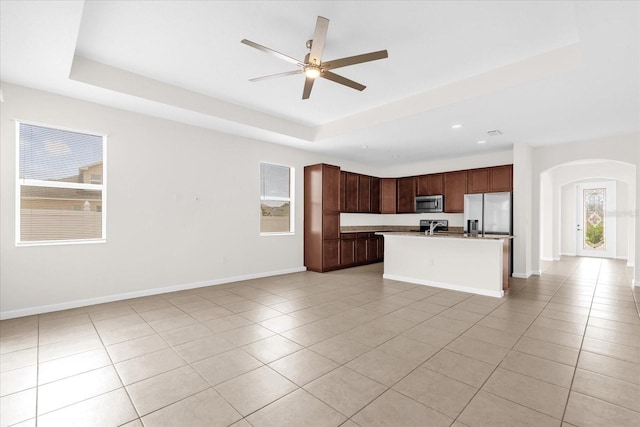 16780 Meadows St, Clermont, FL 34714 - kitchen featuring open floor plan, stainless steel appliances, arched walkways, a raised ceiling, and light tile patterned floors