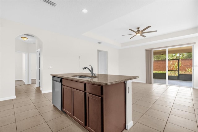 16780 Meadows St, Clermont, FL 34714 - kitchen featuring stainless steel dishwasher, a sink, arched walkways, light tile patterned floors, and dark stone countertops