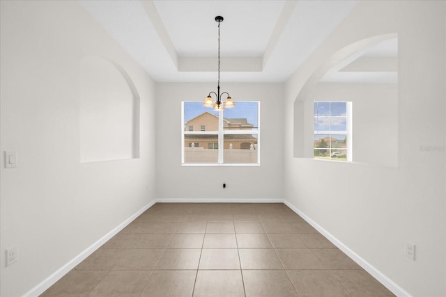 16780 Meadows St, Clermont, FL 34714 - unfurnished dining area with a tray ceiling, baseboards, tile patterned flooring, a chandelier, and arched walkways