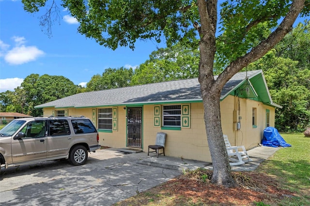 view of front of home with roof with shingles and concrete block siding