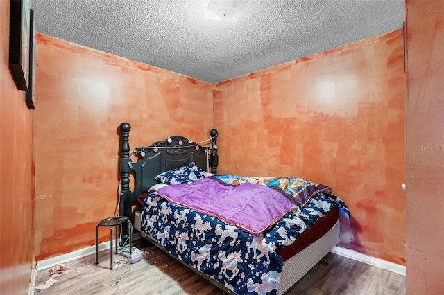 bedroom with baseboards, a textured ceiling, and wood finished floors