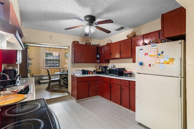 kitchen with freestanding refrigerator, ceiling fan, visible vents, a sink, and light countertops
