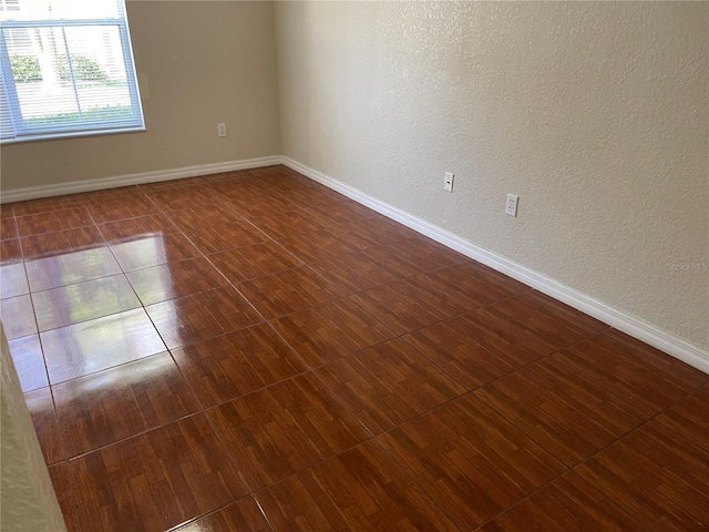 spare room with dark tile patterned floors and baseboards