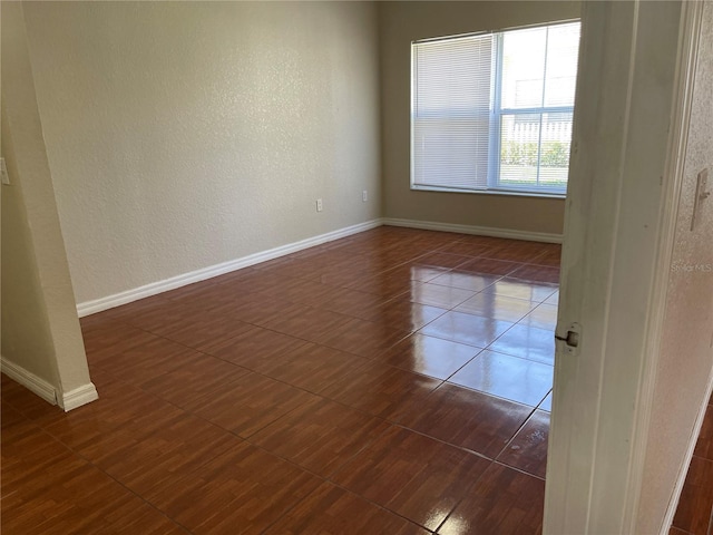 empty room featuring dark tile patterned flooring and baseboards