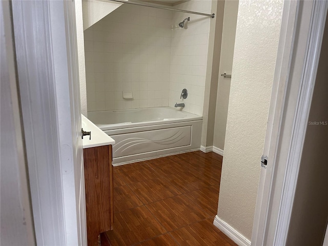 full bathroom featuring shower / bath combination, wood finished floors, baseboards, vanity, and a textured wall