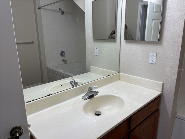 bathroom featuring shower / bath combination, a textured wall, and vanity